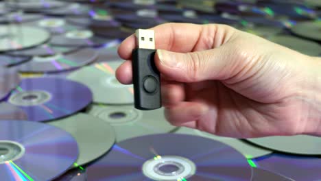 mujer con memoria usb cerca de discos cd y dvd. concepto de tecnología nueva y antigua