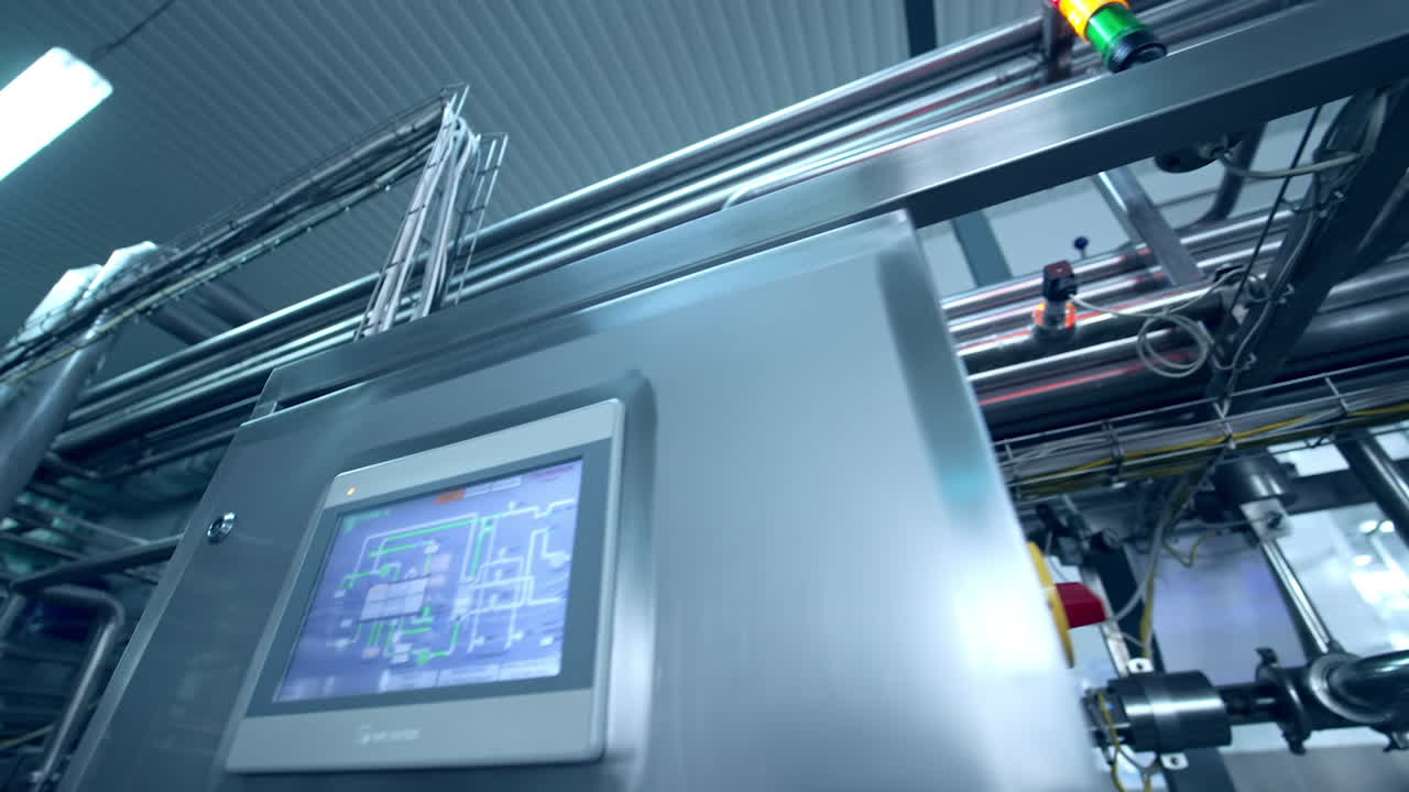 Stainless steel equipment at the diary manufacturing plant. Moving along the numerous pipes at the factory. Metal locker with a screen showing the system of pipelines.