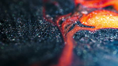 metallic and fiery colors swirl and blend in this macro shot of substances mixing up close