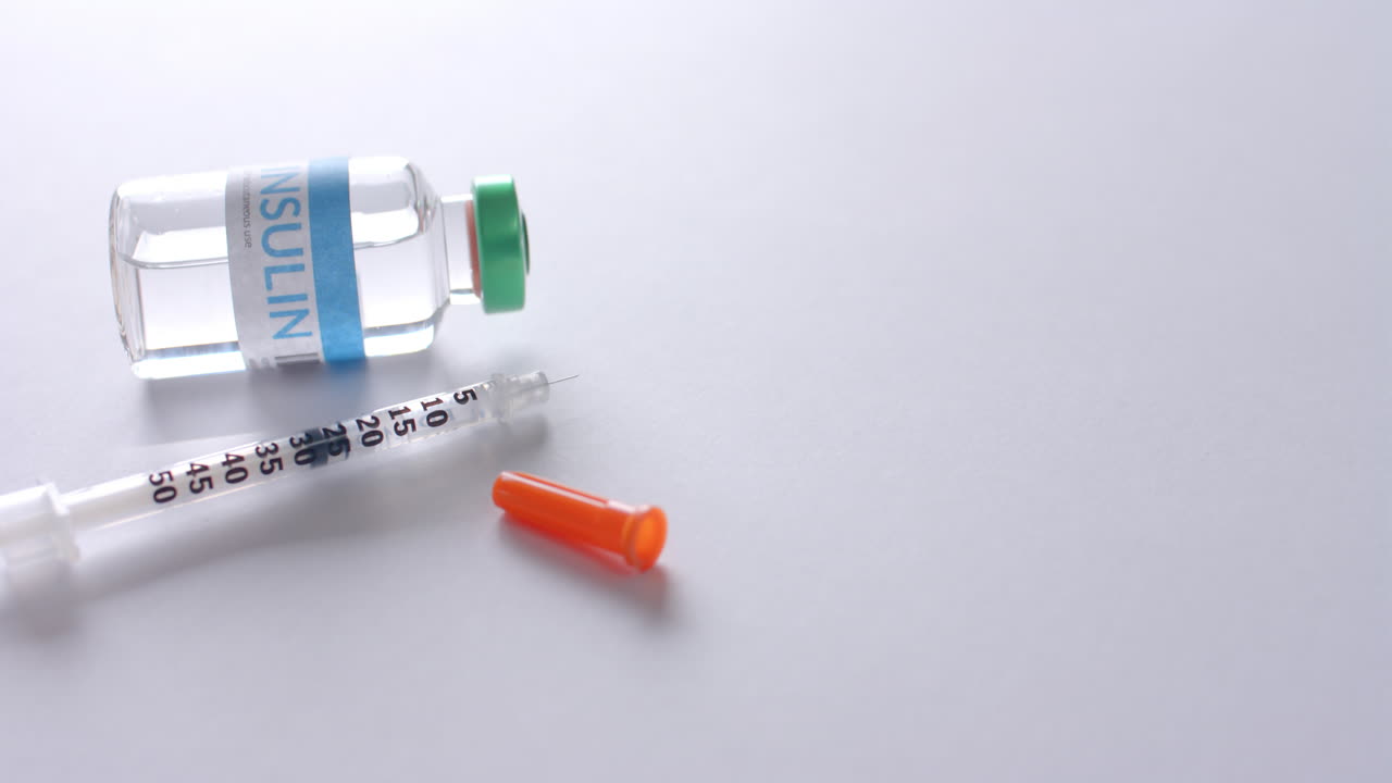 cerrar el vial de insulina y la jeringa sobre un fondo blanco con espacio de copia, cámara lenta.