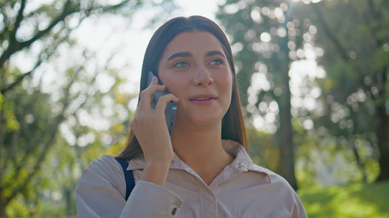 dama positiva disfruta de la conversación telefónica en el parque de verano de cerca. mujer hablando