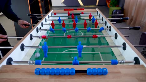 video displays two people - a man and a woman enjoying a break in an office playing table soccer knows as foosball