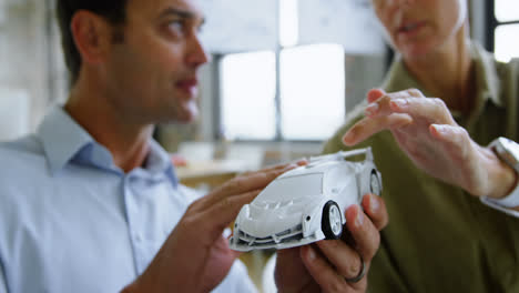 car designers discussing over model car at desk 4k