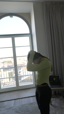 mujer estirándose en una habitación con vista a la ciudad