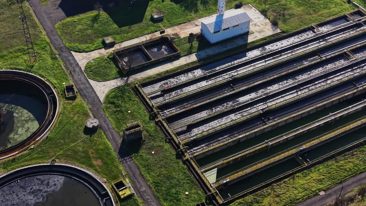 View of sewage treatment facility with tanks and equipment in daytime