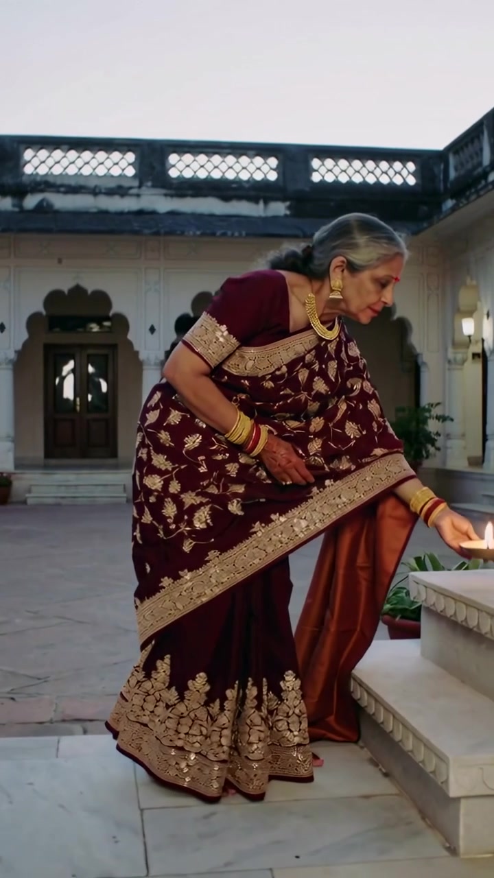 Video verticale: Donna che entra in sari con thali e diya, camminando nel cortile e posizionando una lampada per la preghiera.