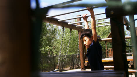 Schoolboy playing on monkey bar in playground