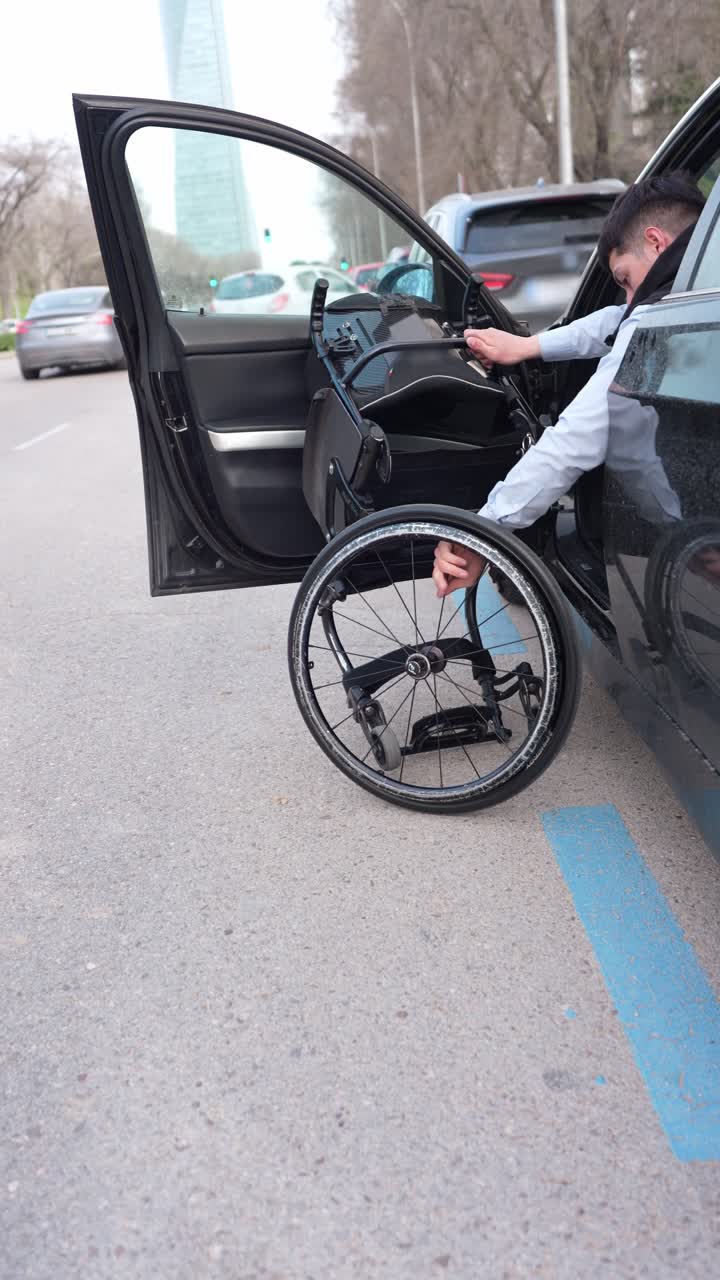 Junger Mann baut Rollstuhl aus Auto auf der Straße zusammen