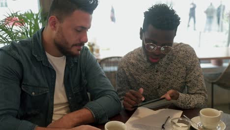 freelancers enfocados bebiendo café y usando teléfonos inteligentes en la cafetería