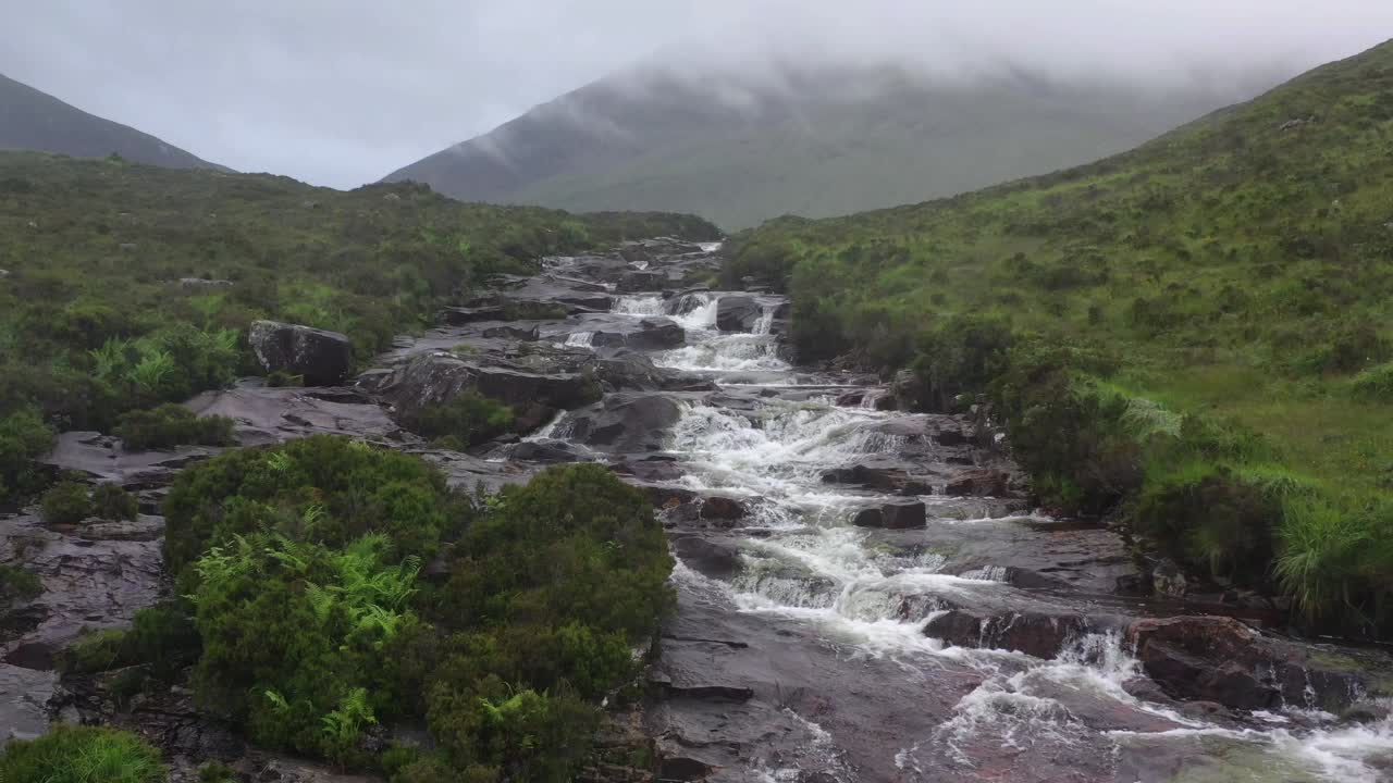 Vista aérea de água em cascata sobre rochas escarpadas na Ilha de Skye.