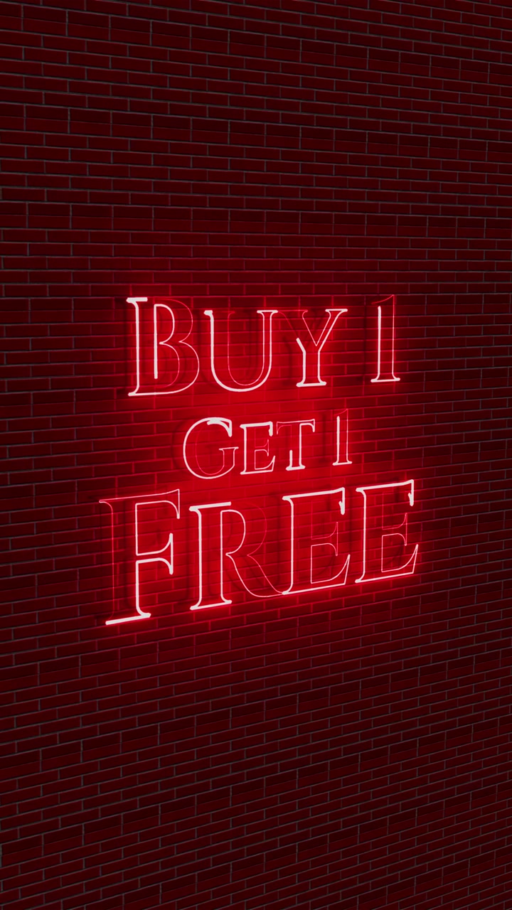 Red neon buy one get one free sign glowing on a brick wall with bright sale message and urban retail