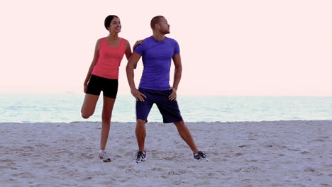 Woman-stretching-and-being-coached-on-the-beach