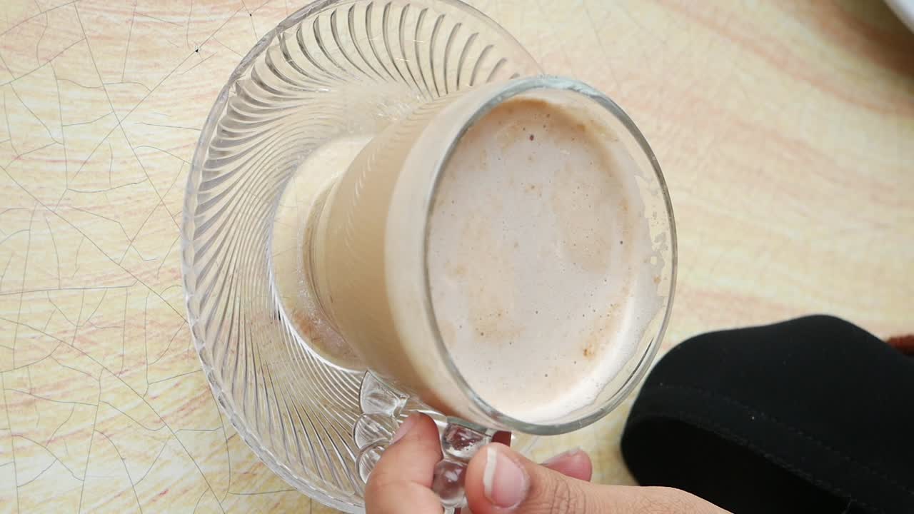 Person holding a glass of coffee or latte