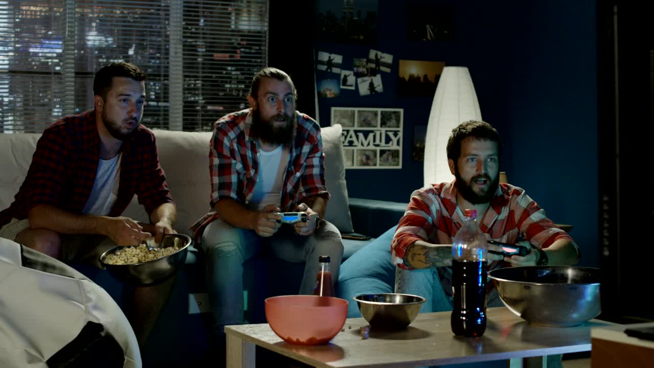 Gruppo di uomini gioca a un videogioco insieme la sera.