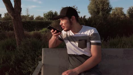 a man is sitting on a bench and looking at his cell phone