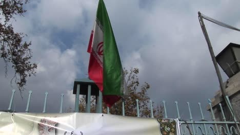 the iranian flag flies atop a gate