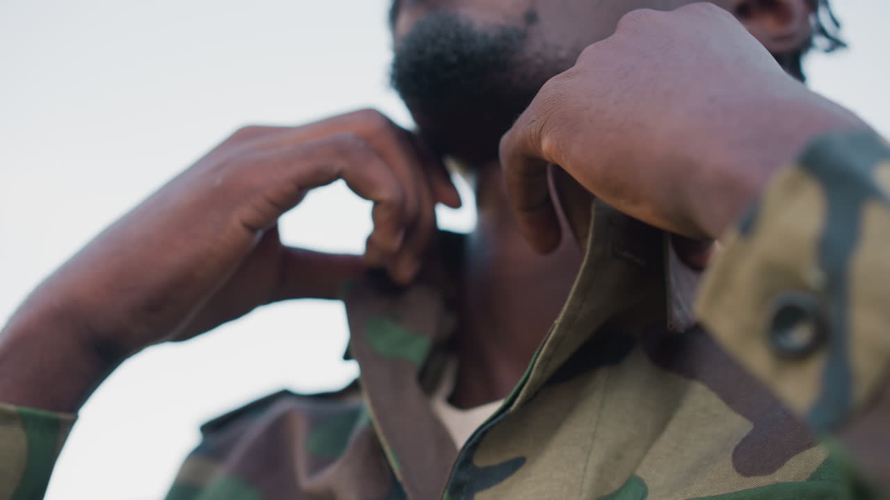 Black Soldier Adjusting Collar With Thoughtful Gaze, Intimate Portrait Framing Shows Face, Hands And Camo Detail In Soft Twilight Moment Of Reflection Before Ceremony Or Mission, Calm And Focused