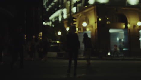 mujer cruzando la calle por la noche en el cruce de peatones en las luces de la ciudad en el centro.