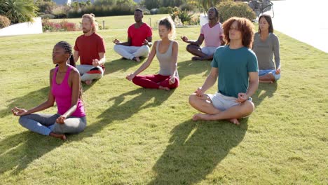 Amigos-Diversos-Enfocados-Practicando-Meditación-De-Yoga-Juntos-Sentados-En-Un-Jardín-Soleado,-Cámara-Lenta