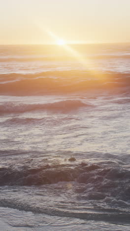 Vertical video of waves on ocean and sunset