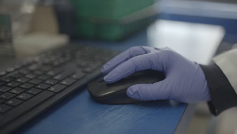 scientist in lab using mouse for computer research with gloves on hand