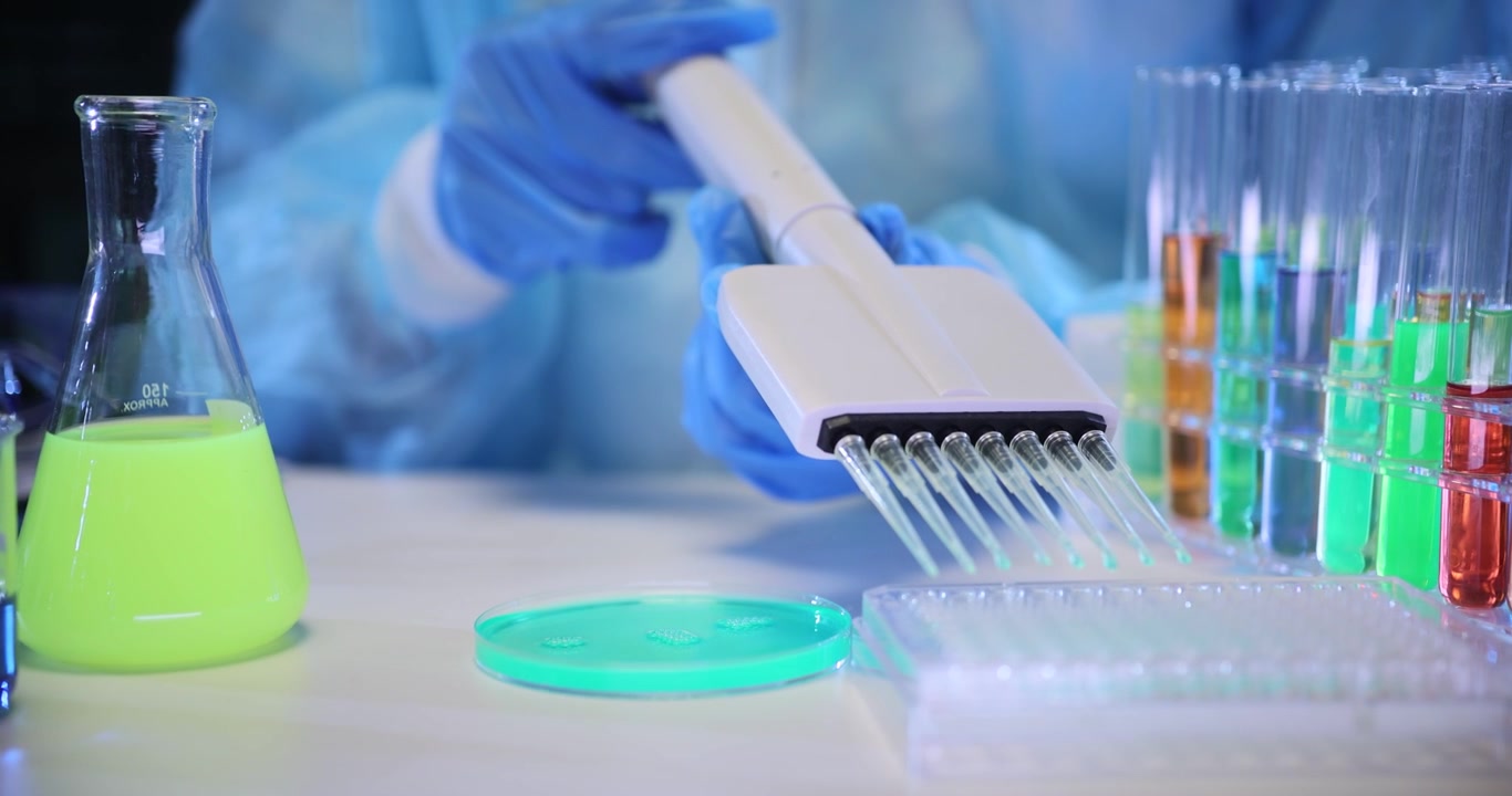 Lab specialist fills test tubes with vivid experimental liquid