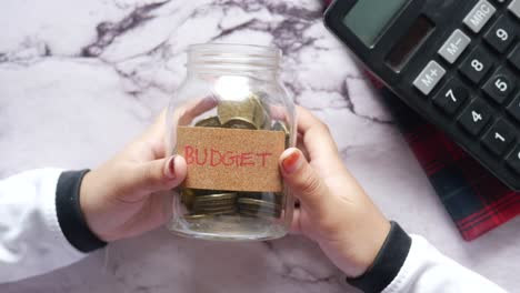 child saving money in a jar with calculator