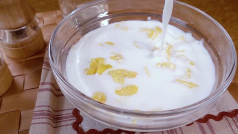 flocos de maíz amarillos crujientes en el cuenco para la mañana un delicioso desayuno con leche. cámara lenta con toma de seguimiento de rotación.