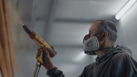 molar sprays paint on steel profiles in a respirator mask and protective suit in slow motion. production and painting studio