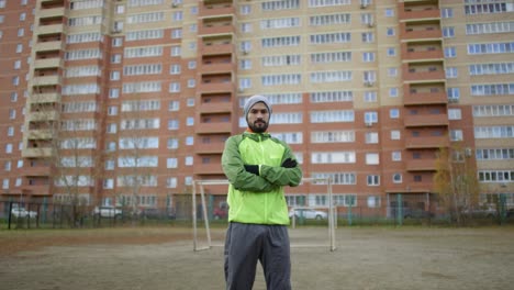 jugador de fútbol masculino confiado mirando a la cámara con los brazos cruzados en el campo