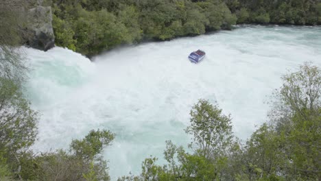 a static wide shot of the end of the huka falls as a jet boat gets close and then leaves frame