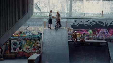 young guys communicating together in skate park with graffiti wall.