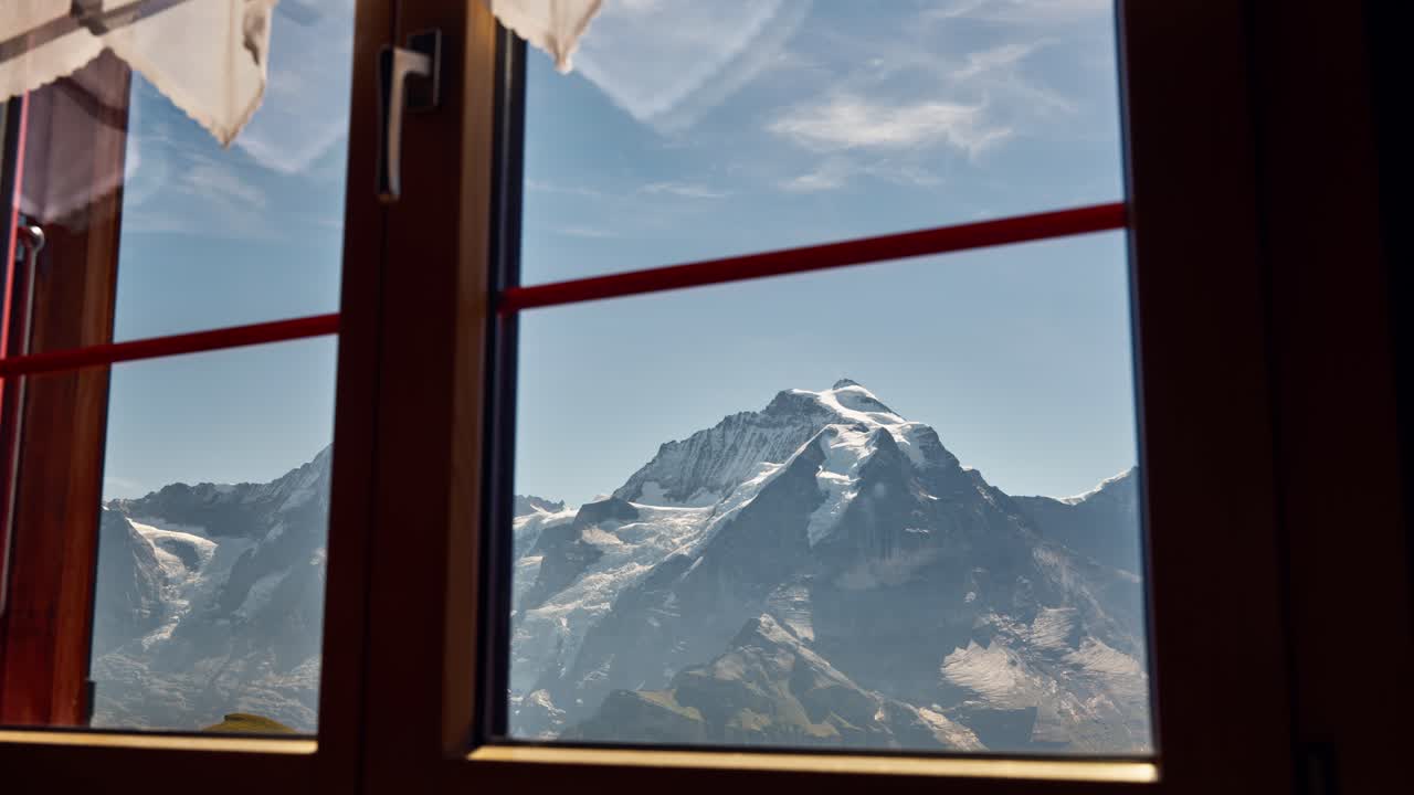 vista de la escarpada cordillera alpina con nieve desde el interior de la casa de vacaciones de montaña, vista desde la ventana