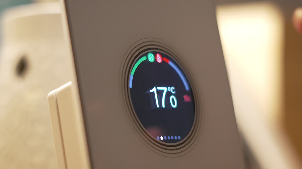 Side View of Finger Adjusting Thermostat from 17°C to 19°C to Heat House During Winter Months. Smart Home Digital Device Being Used Via Internet to Communicate Information