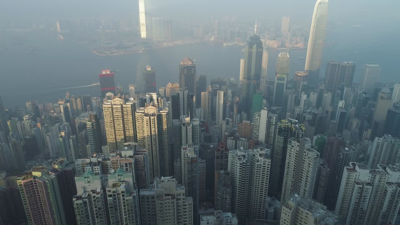 el horizonte de hong kong y el puerto de victoria. vista aérea. el avión no tripulado está volando hacia adelante, la cámara está inclinándose hacia arriba. estableciendo la toma.