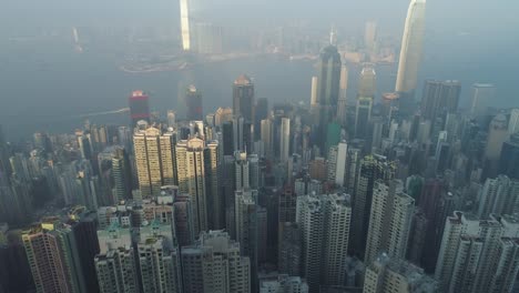 hong kong skyline and victoria harbour. aerial view. drone is flying forward, camera is tilting up. establishing shot.