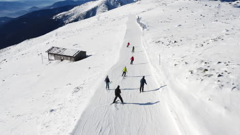 Aerial-view-of-people-skiing-on-a-mountain-ski-slope,-on-a-sunny-winter-day,-in-Slovakia