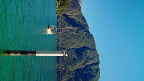 Boat-travels-on-a-sunny-day-near-the-port-of-Lake-Como-in-Italy-surrounded-by-hills