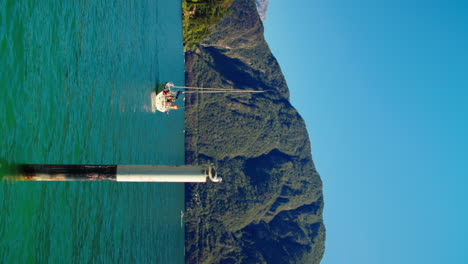 boat travels on a sunny day near the port of lake como in italy surrounded by hills