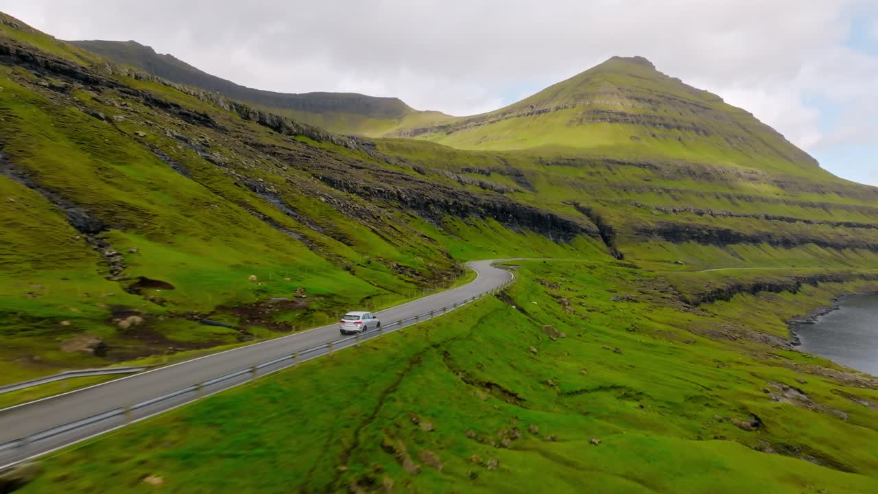 A serene car ride along a winding road in the Faroe Islands with lush green hills