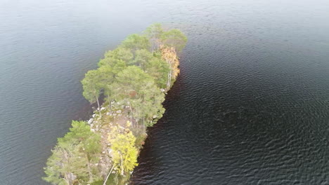 Cabaña-Roja-En-Una-Isla-Aislada-Con-árboles-De-Otoño-En-Un-Lago-Sueco-Durante-El-Día-Nublado