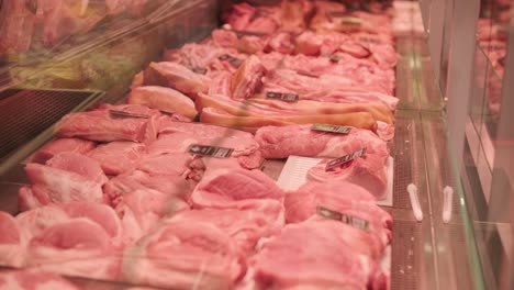 butcher placing raw meat patties into plastic container at meat counter