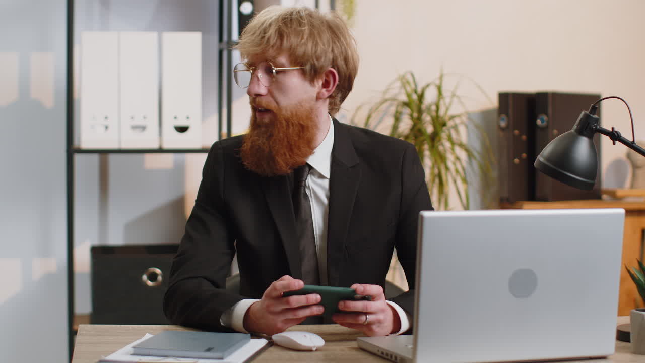 Young business man playing on smartphone exciting mobile application celebrate winning shooter game