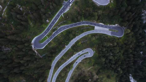 screwdriver drone shot above cars on a serpentine road, gloomy day in the alps
