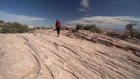 excursionista solitaria en el desierto de utah caminando sobre suelo rocoso, vista posterior, cámara lenta