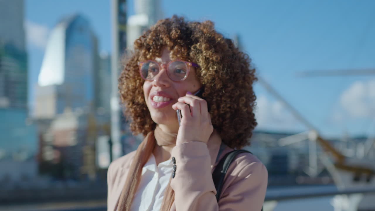 African-American Businesswoman Walking with Coffee Outdoors and Chatting on Phone