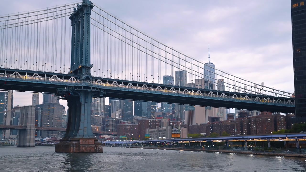 New York, USA, 25. desember 2025: Manhattan Bridge over East River med New Yorks bysilhuett. Stålhengebrokonstruksjon over vann, skyskrapere i bakgrunnen, overskyet himmel, skumringsbelysning, vidvinkelbilde