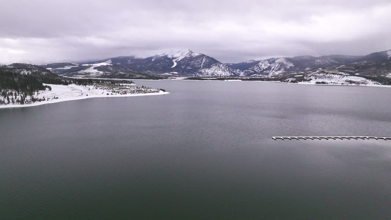 콜로라도 주 런 마리나 호수 (lake dillon marina colorado) 에서 볼 수 있는 공중 영화 드론: 구름이 쌓인 눈이 쌓인 겨울 아침 풍경 (frisco breckenridge, silverthorne, 10mile range, peaceful calm, reflective, frozen ice, backward motion)