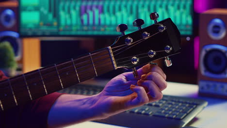 musical performer tuning his guitar by twisting the knobs