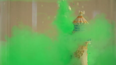 slow motion and close up of a lighthouse underwater with green water ink swirling around it